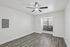 Bright and airy room with modern ceiling fan and large window, showcasing elegant wood-style flooring.