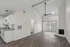 Chic open-plan living room with vaulted ceilings, sleek wooden flooring, modern kitchen, and cozy fireplace, featuring abundant natural light through floor-to-ceiling windows.