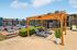 Charming outdoor lounge area featuring stylish sun loungers under a wooden pergola with a view of modern apartment buildings in the background.