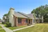 Charming brick townhouse with a modern design, featuring lush green lawn and mature trees, perfect for comfortable suburban living.