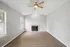 Bright living room with elegant wooden floors, a cozy fireplace, and a modern ceiling fan, ideal for relaxation.