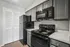 Modern kitchen with sleek black appliances, elegant gray cabinetry, and a pristine louvered pantry door.