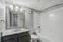 Sleek and modern bathroom with a polished countertop, large mirror, and pristine white bathtub.