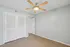 Bright, modern bedroom with sleek laminate flooring, a stylish ceiling fan, and elegant double closet doors.