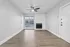 Inviting living room with a sleek ceiling fan, large window for natural light, and a cozy fireplace, complemented by stylish hardwood flooring.