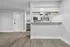 Modern apartment entryway with sleek open kitchen, featuring stylish cabinetry and stainless steel appliances, complemented by elegant wood flooring.