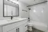 Modern bathroom featuring elegant marble walls, sleek black fixtures, and a stylish vanity with ample storage.