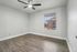 Bright and inviting empty room featuring modern wood flooring, a large window with abundant natural light, and a sleek ceiling fan.