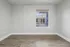Bright and airy room with elegant hardwood flooring and a large window offering a charming view.
