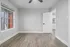 Bright, modern room with stylish wood flooring, large window, and sleek ceiling fan in a spacious apartment.