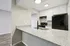 Modern kitchen with sleek granite countertops, double sink, black appliances, and white cabinetry.