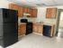 Bright and spacious kitchen with black appliances and wooden cabinets.
