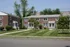 Charming brick apartment building with lush green lawns and mature trees, offering cozy living in a friendly neighborhood.