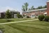 Charming red brick apartment buildings surrounded by lush green lawns and manicured shrubs, offering a serene and welcoming community atmosphere.