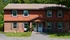 Charming two-story brick and wood apartment building with classic shutters, surrounded by lush greenery at Pine Park Terrace Apartments in Waterford, NY.