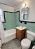 Charming bathroom with vintage aqua tiles, sleek white fixtures, and warm wood accents creating a cozy and inviting space at Adams Park Apartments in Albany, NY.