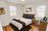 Cozy bedroom with modern decor, featuring a comfortable bed, elegant artwork, and ample natural light through large windows at Adams Park Apartments in Albany, NY.
