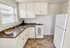 Bright, modern kitchen with sleek white cabinets, elegant countertops, and a stylish tile floor at Adams Park Apartments in Albany, NY.