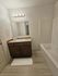 Modern bathroom with bright vanity lighting, a sleek sink, wooden cabinet, and a bathtub.