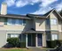 Exterior view of a charming suburban duplex with beige siding and blue shutters under a clear sky.