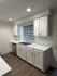 Modern kitchen with white cabinets, marble countertops, and stainless steel appliances.