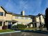 Charming two-story apartment building with vibrant landscaping under a clear blue sky.