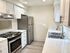 Contemporary kitchen with stainless steel appliances, white cabinetry, and marble countertops.