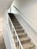 Modern carpeted staircase with sleek white railings and natural lighting.