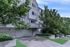 Elegant apartment building with balcony and lush green surroundings.