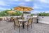 Stylish rooftop patio with dining set and umbrellas, offering city skyline views.