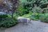 Charming outdoor seating area surrounded by lush greenery in a serene garden setting.