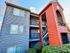 Charming apartment building with vibrant exterior colors and inviting balconies, surrounded by lush greenery.
