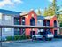 Charming apartment complex with vibrant red and gray exterior, nestled among lush greenery, offering convenient covered parking.