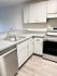 Contemporary kitchen featuring sleek white cabinetry, modern stainless steel appliances, and stylish hardwood flooring.
