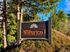 Welcoming entrance sign for Wilburton I Apartments surrounded by lush greenery and tall trees.