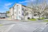 Charming three-story apartment building with balconies, surrounded by greenery and a serene neighborhood setting. Ideal for urban living with ample parking space.