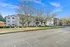 Modern apartment complex with charming balconies, lush greenery, and clear blue skies in a serene neighborhood setting.