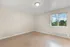 Bright, spacious room with elegant hardwood flooring and a large window showcasing lush greenery outside.