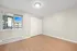 Bright, spacious room with modern wood flooring and a large window offering a view of the outdoor architecture.