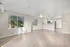 Bright open-plan living area with hardwood floors, large windows, and a modern kitchen in a cozy apartment space.