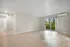 Bright and spacious living area with light hardwood floors, large windows overlooking scenic greenery, and modern air conditioning.