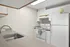 Charming modern kitchen with sleek white cabinets, stainless steel sink, and a spacious countertop, perfect for culinary enthusiasts.