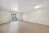 Bright, spacious living room with sleek hardwood floors and a large glass door balcony access, perfect for modern urban living.