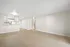 Bright open-concept apartment with modern kitchen and spacious living area, featuring sleek light wood flooring.