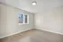 Bright and airy room with sleek wooden flooring and a large window offering a serene view, perfect for a cozy bedroom or office space.
