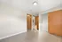 Bright, minimalist bedroom with sleek wood floors, warm wooden doors, and an inviting open closet space.