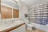 Modern bathroom featuring elegant fixtures, a large mirror, and tasteful striped shower curtain.