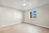 Bright and airy bedroom with large window showcasing a serene view, featuring sleek hardwood floors and neutral walls.