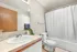 Bright and modern bathroom featuring a sleek sink, elegant countertop, and a spacious bathtub with a stylish white shower curtain.