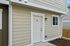Charming apartment entrance with a modern light fixture and neutral siding.